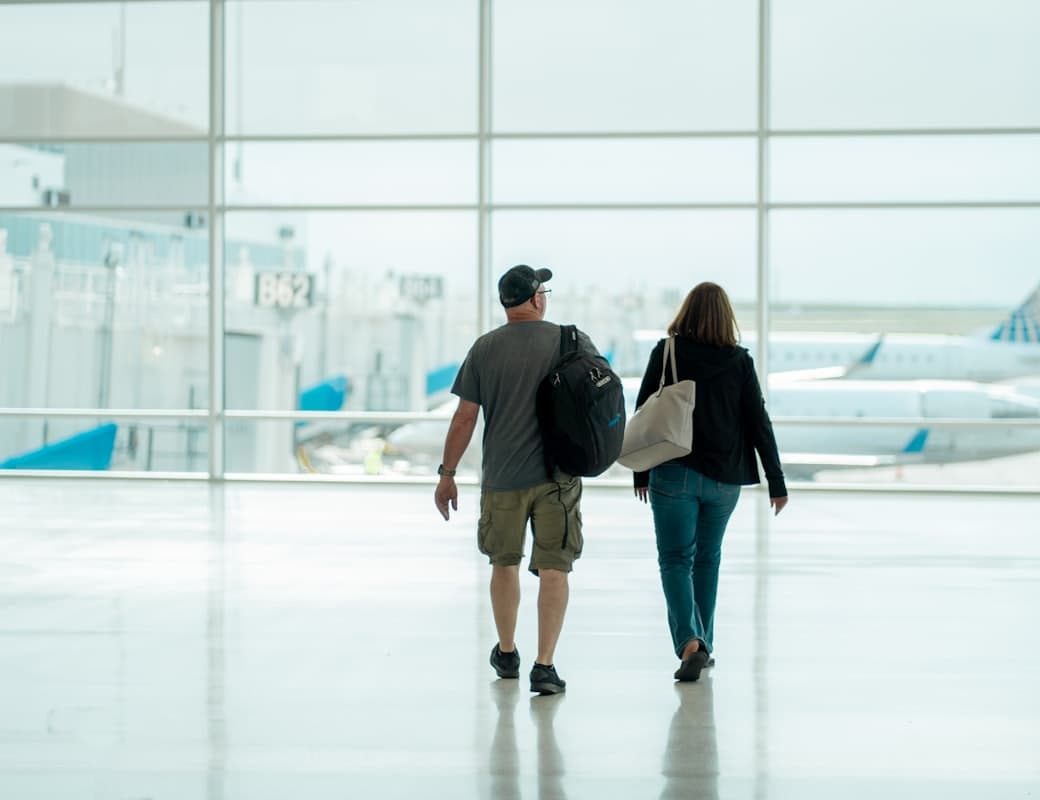 Two travellers walking together through an airport terminal